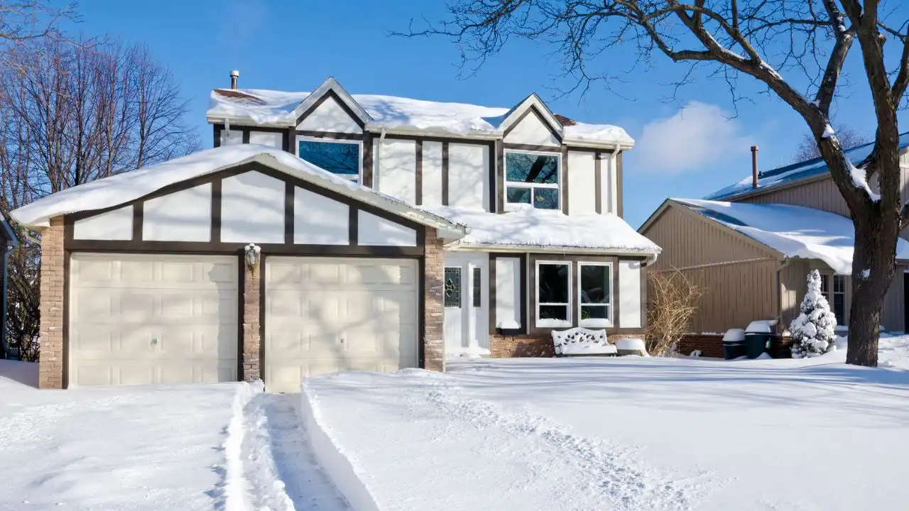 Snow-covered home with a double garage; garage door won't close when cold weather causes problems